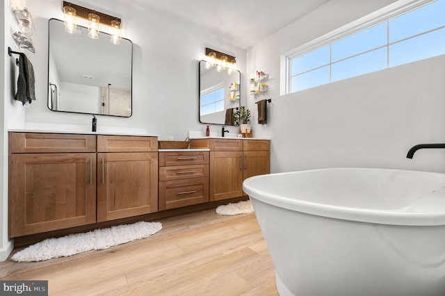 bathroom featuring a tub to relax in, wood-type flooring, and vanity