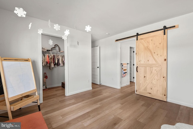 bedroom featuring light hardwood / wood-style floors, a closet, a walk in closet, and a barn door