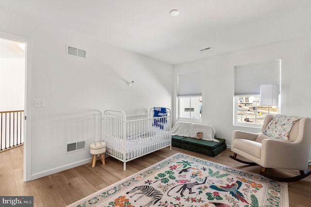 bedroom featuring wood-type flooring and a nursery area