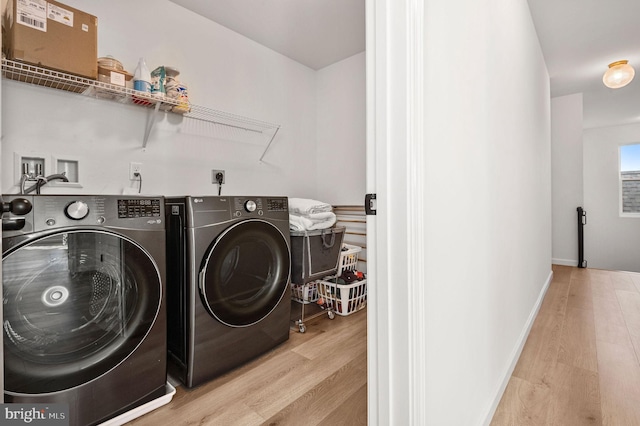 clothes washing area featuring separate washer and dryer and light hardwood / wood-style floors