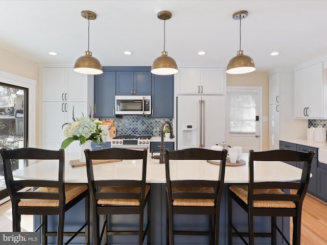 kitchen featuring a breakfast bar, pendant lighting, blue cabinets, a kitchen island with sink, and high end fridge