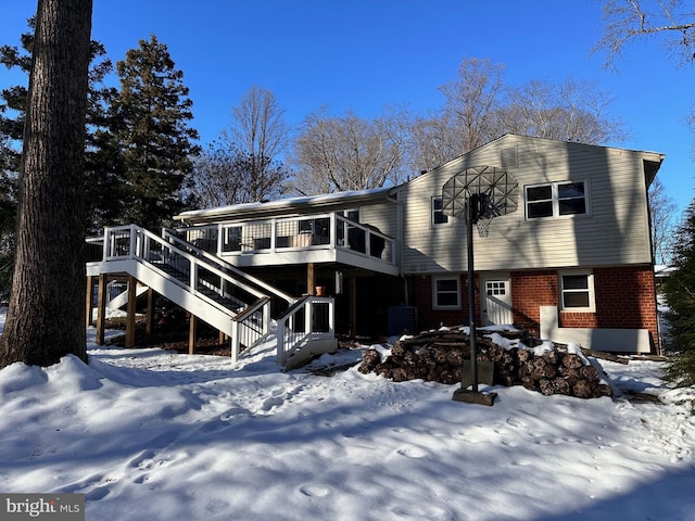 snow covered rear of property with a deck