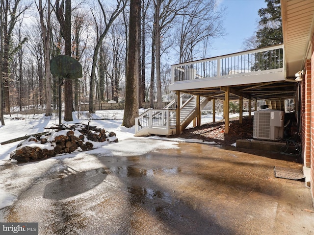 yard layered in snow with a wooden deck and central AC unit