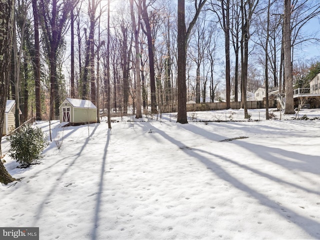 snowy yard featuring a storage shed