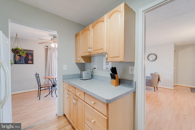 kitchen featuring ceiling fan, white fridge with ice dispenser, light wood-type flooring, and light brown cabinets