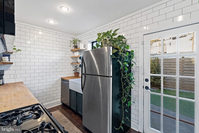 kitchen featuring stainless steel appliances, butcher block counters, and dark wood-type flooring