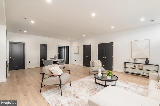 living room with recessed lighting, visible vents, baseboards, and light wood finished floors