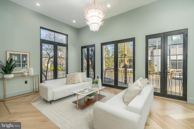 living area featuring baseboards, a high ceiling, recessed lighting, french doors, and a chandelier