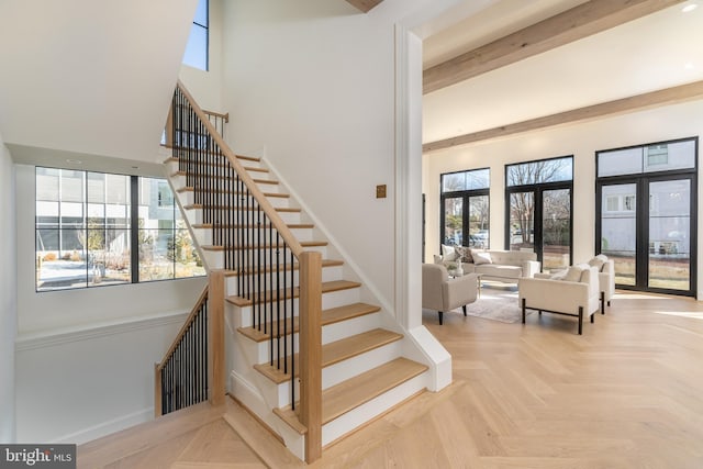 stairway with beam ceiling, a high ceiling, and baseboards