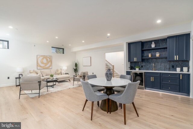 dining area featuring light wood finished floors, wet bar, recessed lighting, stairs, and wine cooler