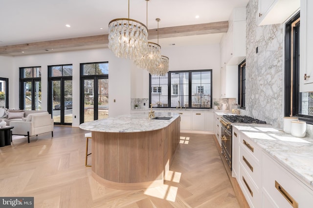 kitchen with a sink, beamed ceiling, light stone counters, and backsplash