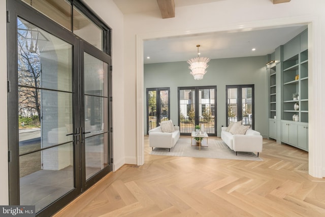 living area featuring baseboards, built in features, recessed lighting, french doors, and a notable chandelier