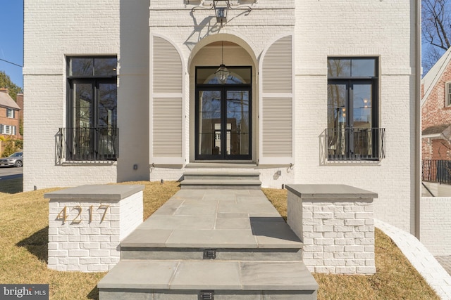 view of exterior entry featuring brick siding and french doors