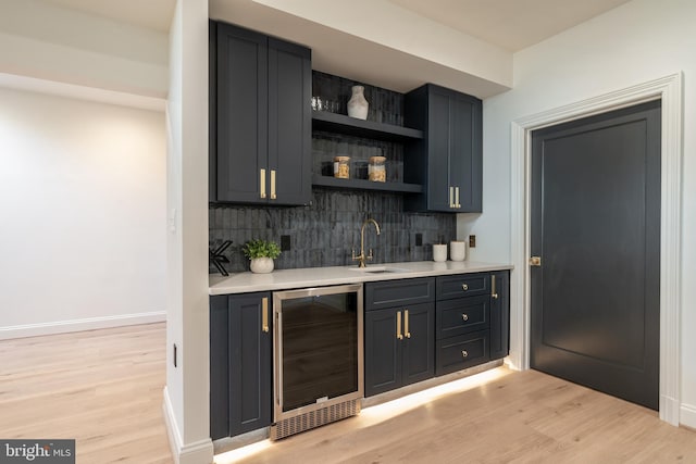 bar featuring beverage cooler, indoor wet bar, light wood-type flooring, and a sink