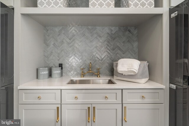 kitchen featuring a sink, tasteful backsplash, refrigerator, freestanding refrigerator, and light countertops