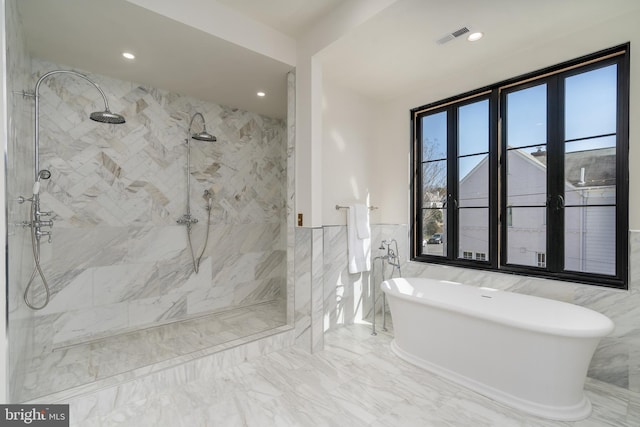 full bathroom with a freestanding tub, a wainscoted wall, visible vents, marble finish floor, and tiled shower