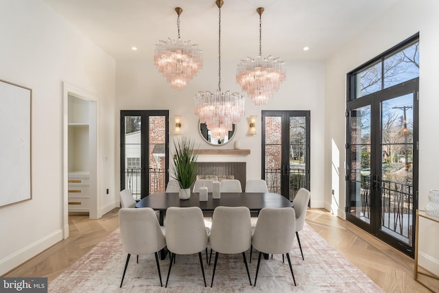 dining area with baseboards, recessed lighting, french doors, a towering ceiling, and a notable chandelier