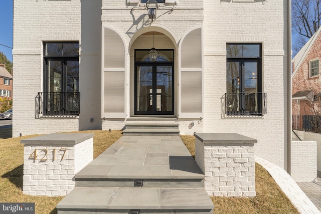 property entrance featuring french doors and brick siding