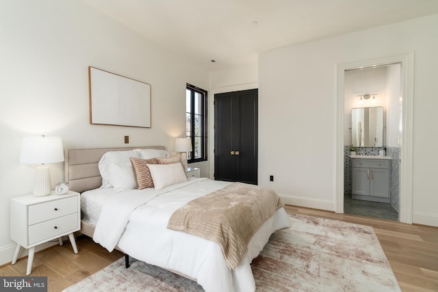 bedroom featuring light wood finished floors, connected bathroom, and baseboards