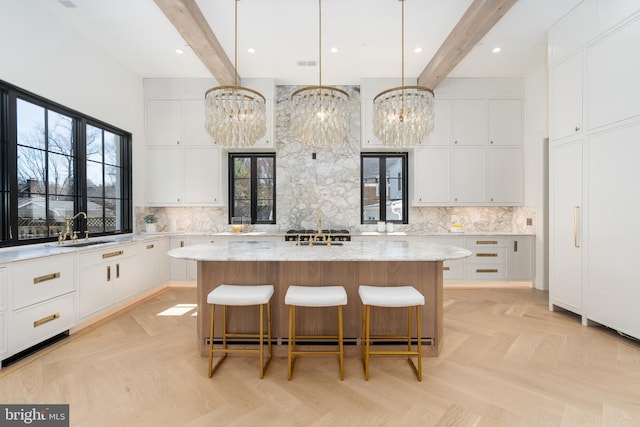 kitchen with a kitchen bar, beamed ceiling, a sink, tasteful backsplash, and a center island