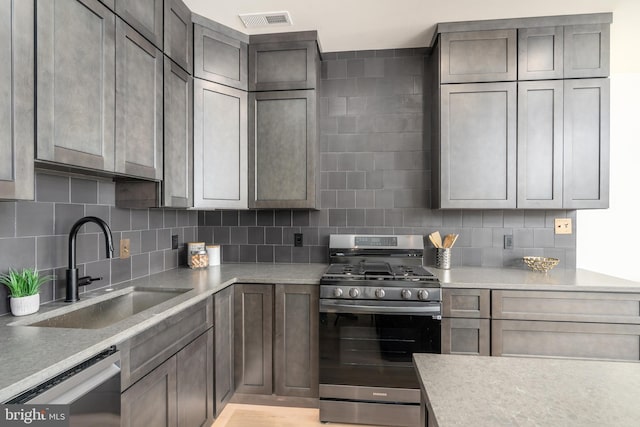 kitchen with visible vents, a sink, dishwasher, gas range, and backsplash