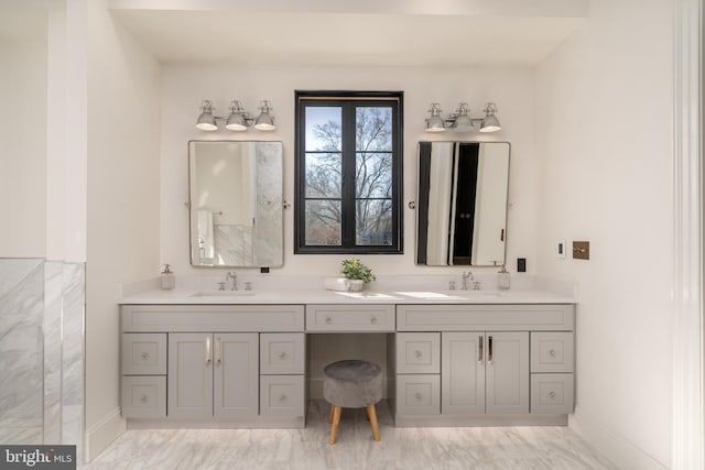 full bathroom featuring a sink, marble finish floor, baseboards, and double vanity