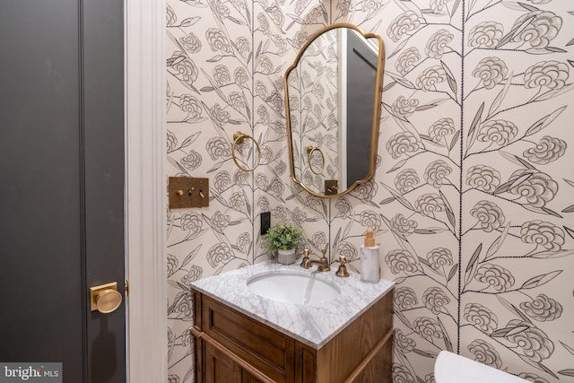 half bathroom featuring wallpapered walls and vanity