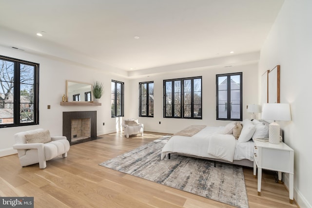 bedroom with a fireplace with flush hearth, recessed lighting, baseboards, and light wood-style floors