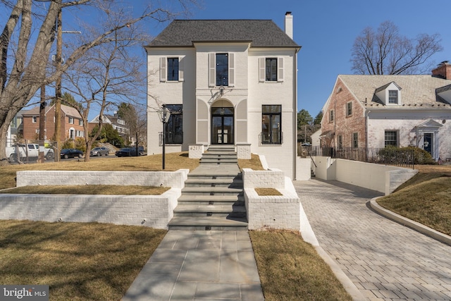 view of front of property with fence, roof with shingles, a chimney, french doors, and brick siding