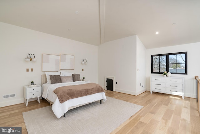 bedroom with visible vents, baseboards, light wood-style floors, and vaulted ceiling