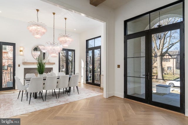 dining space with an inviting chandelier, a high ceiling, french doors, and baseboards