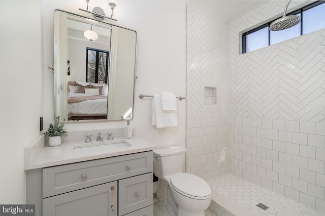 full bathroom with vanity, toilet, a tile shower, and connected bathroom