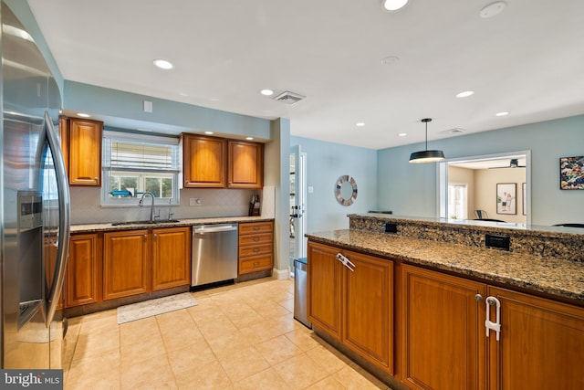 kitchen featuring pendant lighting, backsplash, dark stone counters, appliances with stainless steel finishes, and sink