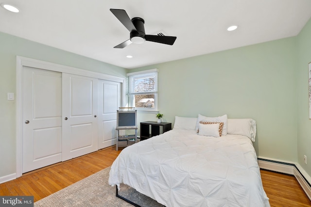 bedroom featuring ceiling fan, hardwood / wood-style floors, a closet, and a baseboard radiator