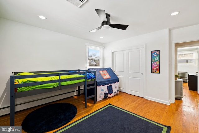 bedroom with a baseboard heating unit, ceiling fan, and light hardwood / wood-style floors