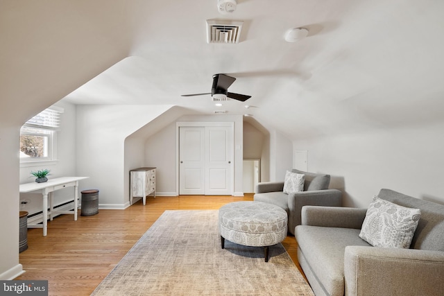 living area with vaulted ceiling, a baseboard radiator, ceiling fan, and light hardwood / wood-style floors