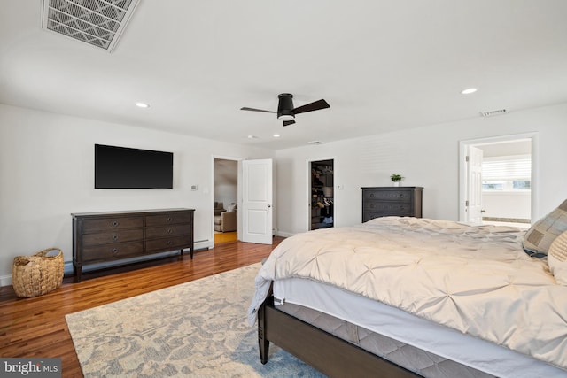 bedroom with wood-type flooring, a closet, ceiling fan, and a walk in closet