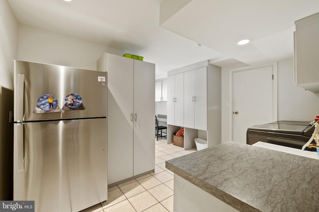 kitchen featuring washer / dryer, light tile patterned flooring, and stainless steel refrigerator