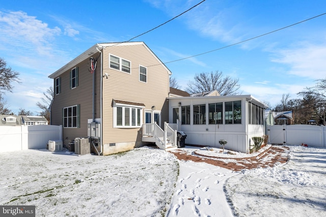 snow covered property with cooling unit and a sunroom