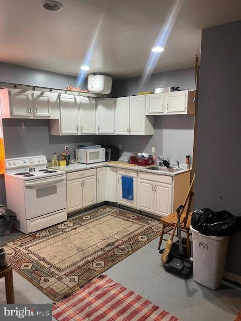 kitchen with white cabinetry, sink, and white appliances