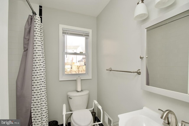 bathroom featuring toilet, sink, and a shower with curtain