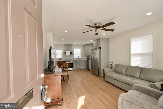 living room with ceiling fan, a healthy amount of sunlight, sink, and light hardwood / wood-style floors