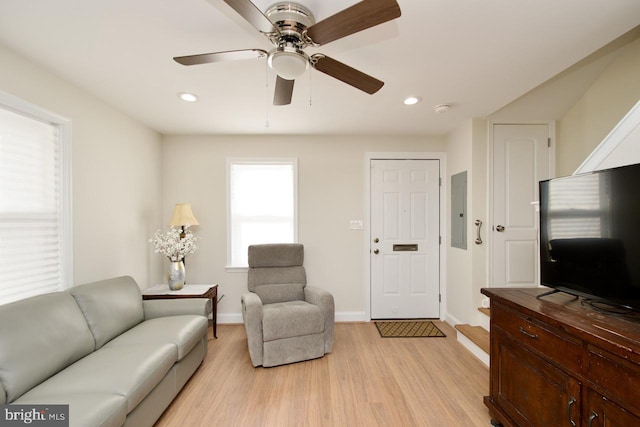 living room with ceiling fan, electric panel, and light hardwood / wood-style flooring