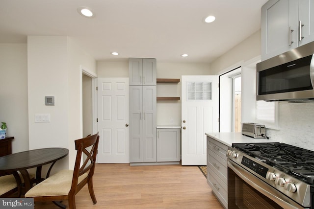 kitchen featuring gray cabinets, tasteful backsplash, appliances with stainless steel finishes, and light hardwood / wood-style floors