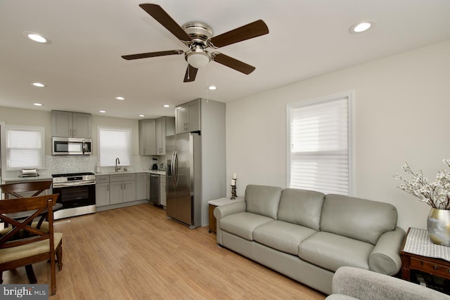 living room featuring ceiling fan, sink, and light hardwood / wood-style floors