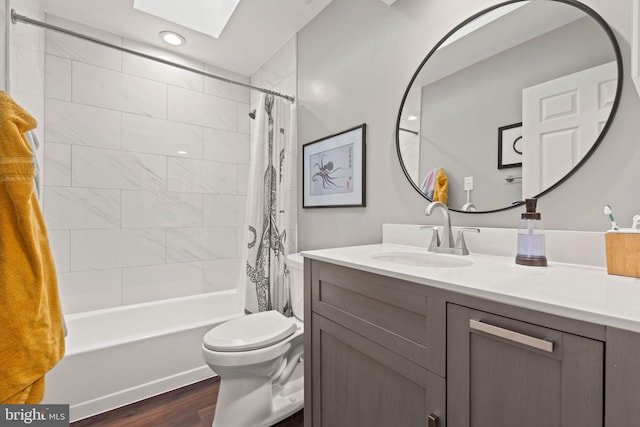 full bathroom with hardwood / wood-style floors, a skylight, vanity, shower / tub combo, and toilet