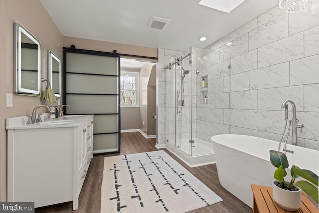 bathroom with vanity, hardwood / wood-style floors, a skylight, and plus walk in shower