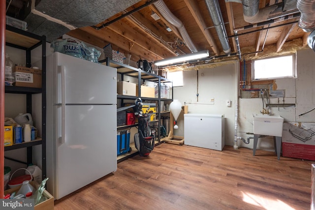 basement with wood-type flooring, white fridge, and refrigerator