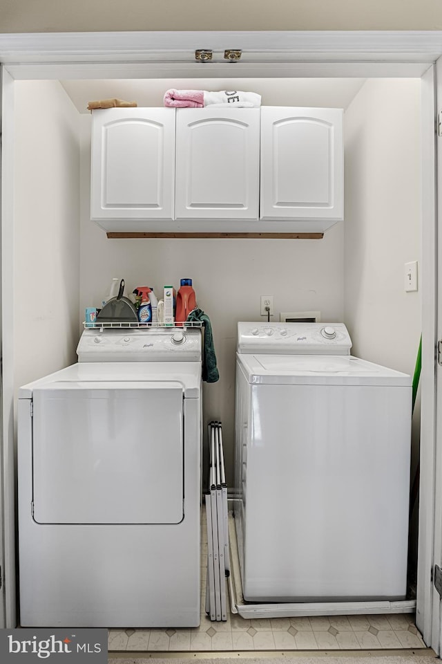 laundry room with washing machine and clothes dryer and cabinets