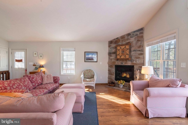 living room featuring lofted ceiling, a fireplace, and wood-type flooring